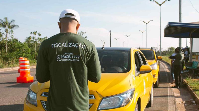 Foto 2: Fiscal da Arsepam parado na frente de um táxi que opera o transporte rodoviário intermunicipal
